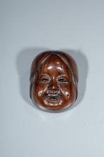 Een Japanse boxwood netsuke die het masker van Okame