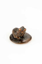 Een houten netsuke van een Pekingese puppy zittend op een