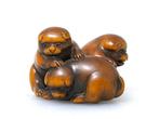 Netsuke afgebeeld met drie speelse puppys, geïllustreerd in
