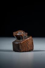 Een netsuke van buxushout met een kikker die op een
