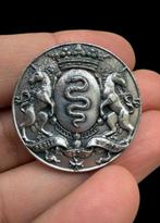 Vreemde militair heraldiekspeld in zilverkleurig metaal,