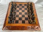 Schaakspel - Spelbord van hout met reliëf en bronzen figuren