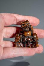 Een Japanse netsuke van boxwood met drie figuren tijdens het