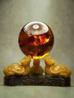 3 Baltische barnsteen draken die een barnsteenbal vasthouden