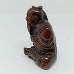 Vreemde netsuke die een personage met een hossu-stok