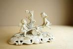 Triade - Beeldje - Winged putti on seesaw - Biscuit